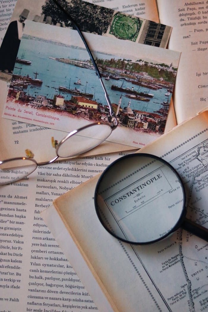 Flat lay of vintage maps with eyeglasses and magnifying glass, evoking exploration.